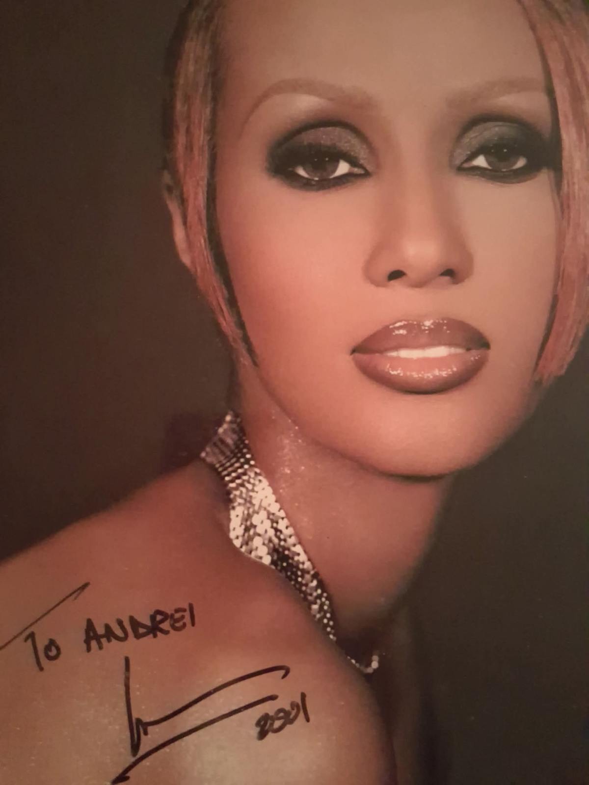 Printed portrait photograph of Iman with short light hair, heavy dark eye makeup and glossy lips, signed and dedicated to Andrei in black marker
